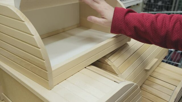 Girl in a store buys a wooden container for storing bread and food. The concept of buying new dishes and kitchen equipment. Hands close up shot