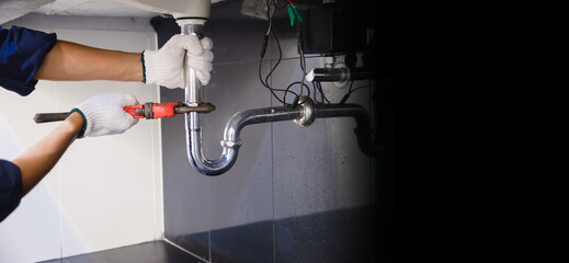 Plumber fixing white sink pipe with adjustable wrench.