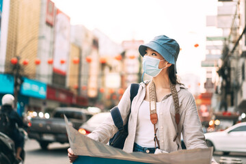 Young adult traveller asian woman wear face mask for virus using map for travel in city.