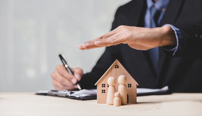 Insurance house, and family health live concept. The insurance agent presents the ้hands protection model that symbolize the coverage.