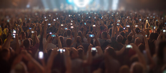people at a concert are filming on a smartphone.