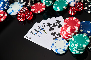Casino chips, playing cards and dices on dark reflective background