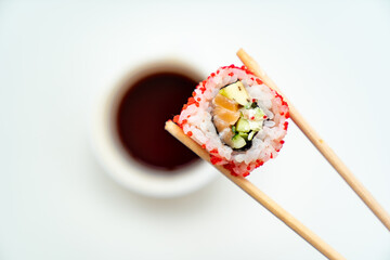 sushi sticks keep roll with a cup of soy sauce on white background