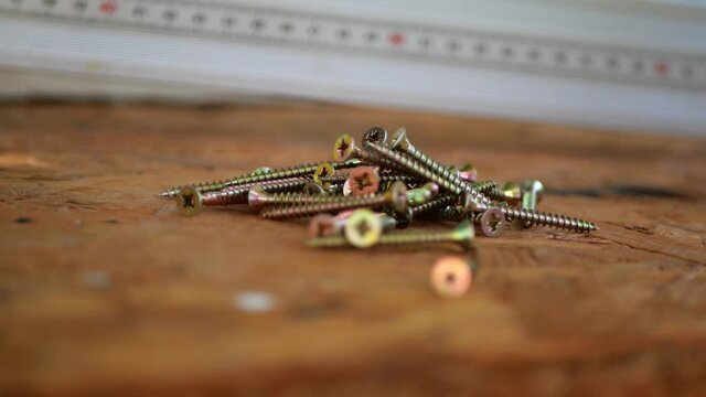 Flat head screws for plywood pour out of human hand. Pouring bolts in three rounds, close up