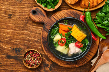 Chilean meat soup with pampkin, corn, fresh coriander and potatoes on old wooden table background. Cazuela. Latinamerican food.