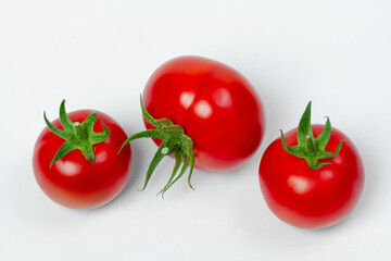 Three red fresh tomatoes on a light background. View from above. Vegetarian food concept.