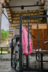 Black and metal border fences covers the antique mosque in iznik and there is pink color clothes on the fence