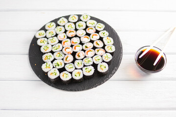 Japanese sushi set served on the black plate with traditional plates and chopsticks on the background
