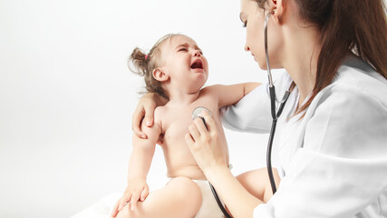 baby at the doctor pediatrician. doctor listens to the heart with a stethoscope cry baby