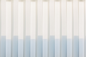 Abstract geometric vertical lines white and gray gradient color. Repeating pattern, background texture, design of striped lines. Blinds illuminated by the sun, close-up.