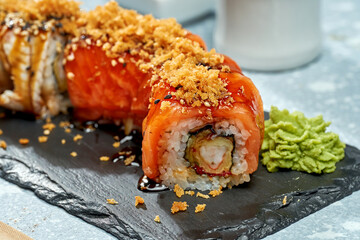 Sushi roll philadelphia with salmon, shrimp and eel on a black plate on a light background