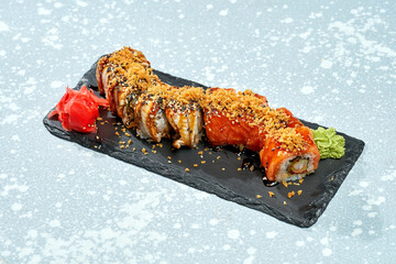 Sushi roll philadelphia with salmon, shrimp and eel on a black plate on a light background