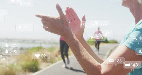 Animation of social media notifications, over woman clapping women running by beach - Powered by Adobe