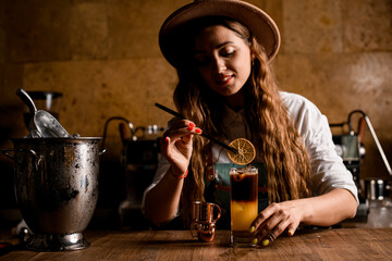 young woman neatly decorates glass with bumble coffee with slice of orange
