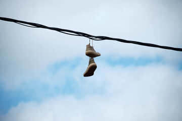 Paire de chaussures suspendues à un câble électrique . - obrazy, fototapety, plakaty