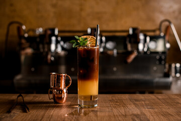 Bumble coffee from americano and orange juice in layers in transparent glass on table