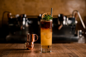 Glass of colorful cocktail with orange juice and espresso coffee on wooden table