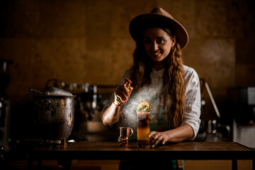 young attractive woman bartender skillfully splashes on glass with cold orange coffee cocktail