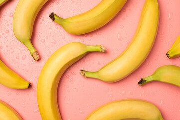 Top view photo of ripe yellow bananas and water drops on isolated pastel pink background