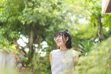 Portrait of young adult asian woman face wear eyeglasses and short hair stay at home in green garden yard on day.