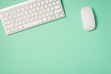 Top view photo of white wireless keyboard and mouse on isolated turquoise background with copyspace