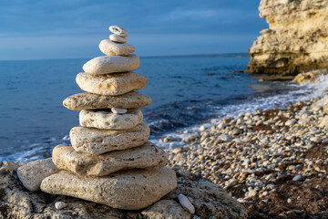 Balanced stones pyramid on pebble beach on sunny day and clear sky at sunset. Symbolizes stability, zen, harmony, balance, meditation, spa, harmony, calm concept