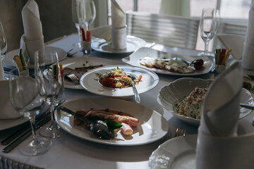 Table setting for a banquet or celebration. Empty wine glasses for spirits, champagne and juice. Set the table. Cloth napkins on a platter. Banqueting hall. Cold appetizers and salads