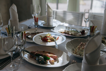 Table setting for a banquet or celebration. Empty wine glasses for spirits, champagne and juice. Set the table. Cloth napkins on a platter. Banqueting hall. Cold appetizers and salads