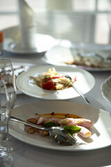 Table setting for a banquet or celebration. Empty wine glasses for spirits, champagne and juice. Set the table. Cloth napkins on a platter. Banqueting hall. Cold appetizers and salads