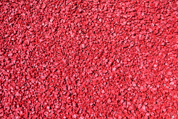 Red stones on a flowerbed on a sunny day, background image.