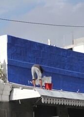 Man painting wall panel in blue