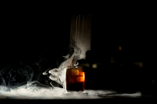 Beautiful Old-fashioned Glass Of Cold Drink In Dark Bar With Wonderful White Smoke Around