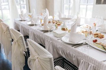 Table setting for a banquet or celebration. Empty wine glasses for spirits, champagne and juice. Set the table. Cloth napkins on a platter. Banqueting hall. Cold appetizers and salads