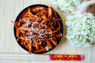 Kinpira carrots with sesame seeds, Japanese side dish, styled with chopsticks and hydrangea