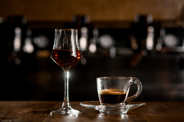 glass of cognac and transparent cup with espresso on the table. Blurred background