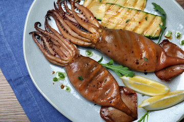 Delicious grilled squids served on wooden table, top view