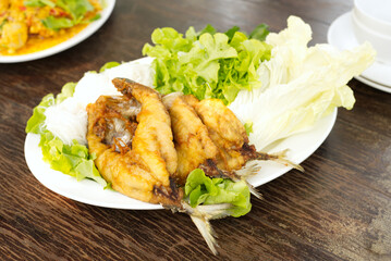 thai food Fried Mackerel Miang with lettuce, white cabbage, white rice noodles in a white dish Place on a brown wooden dining table.