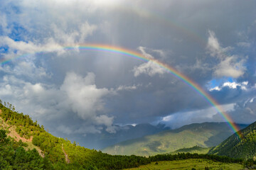 A rainbow among mountains in cloudy day