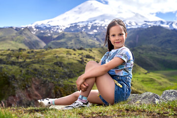 a little cute girl on the background of mountain peaks.