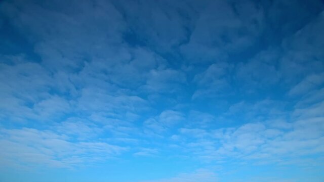 Low-angle shot of floating white clouds in blue sky, time-lapse