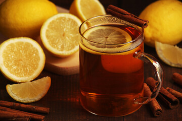 A mug with hot tea with lemons and cinnamon sticks
