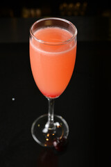bartender special cold pink fruit punch cocktail wine or mocktail with cherry pop juice in tall glass goblet on black background luxury hotel pub iced beverage menu
