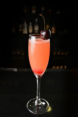 bartender special cold pink fruit punch cocktail wine or mocktail with cherry pop juice in tall glass goblet on black background luxury hotel pub iced beverage menu