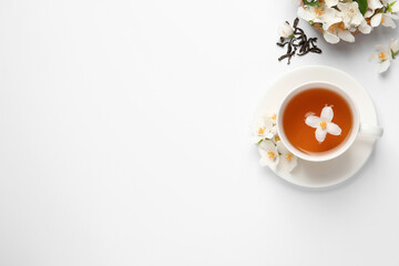 Obraz na płótnie Canvas Cup of aromatic jasmine tea and fresh flowers on white background, top view. Space for text