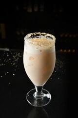bartender special cold peanut or almond cocktail mocktail with fresh coconut milkshake juice in tall glass goblet on black background luxury hotel pub iced beverage menu