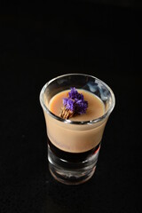 bartender special cold peanut almond cocktail / mocktail with coconut milkshake and flower in glass goblet on black background luxury hotel pub iced beverage menu