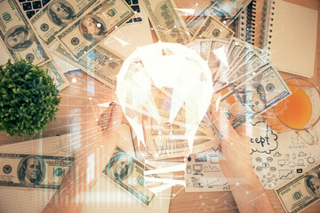 Multi exposure of bulb drawing hologram and USA dollars bills and man hands. Business Idea concept.