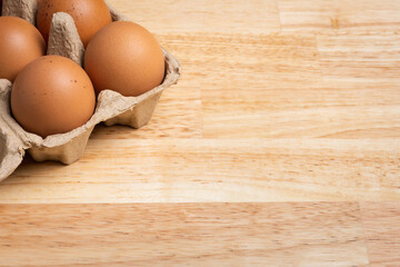 Chicken eggs in carton box on wooden table.