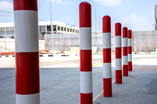 Row of red and white traffic barrier pole on car parking lot.