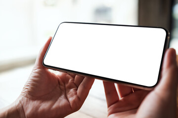 Mockup image of a woman holding mobile phone with blank white desktop screen